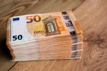 Euro money banknotes. Bundle of 50 euro bills on wooden table. Stack of euros banknotes, Money big...