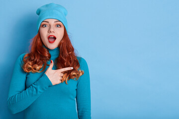 Astonished Caucasian woman indicates away, shows blank space for your advertisement, red haired...