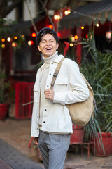 Stylish man walking down the street wearing white  sweater and jacket laughing on street
