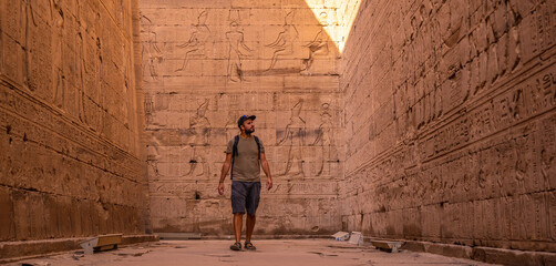 A young tourist visiting the beautiful temple of Edfu in the city of Edfu, Egypt. On the bank of...