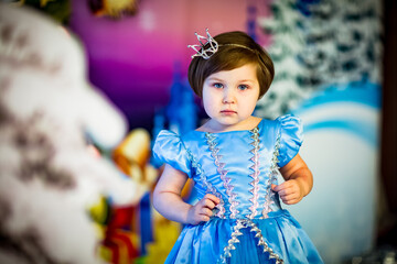 a small ,beautiful girl in a Princess carnival dress,standing near the scenery in the new year's holiday