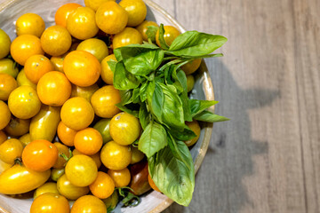 Golden yellow cherry tomatos with basil on wooden table