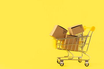 Toy shopping cart with boxes in female hand over blue background. Copy space for text or design....