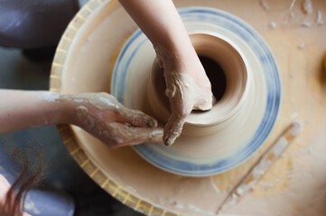 Fototapeta premium Female hands in a pottery workshop close-up, top view.
