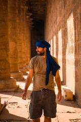 Young man in blue turban visiting the Edfu Temple near Aswan city. Egypt, west bank of the nile in...