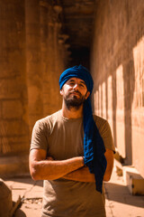 Portrait of a young man in a blue turban visiting the Edfu Temple near the city of Aswan. Egypt,...