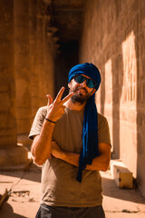 A young tourist in a blue turban visiting the Edfu Temple in the morning near Aswan city. Egypt,...