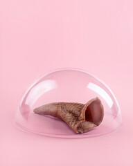 Creative layout made with ice cream cone under the dome on a pink background. Concept of COVID-19 quarantine. World pandemic concept. Stay at home. Flat lay.