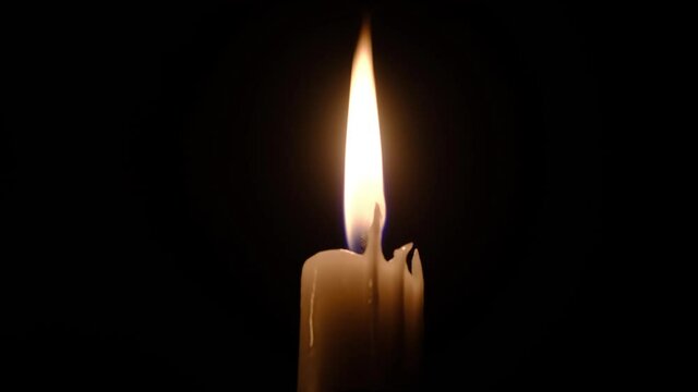Candle Flame in Romantic Mood on a Black Background. Glowing With Soft Candle Light. Background or illustration of remembrance or celebration