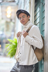 Stylish man wearing white  sweater and jacket  and standing on street