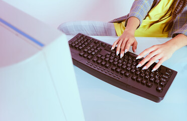 Female hands with beautiful manicure typing on black keyboard, close up