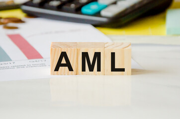 Money laundering concept. AML - Anti-Money Laundering - Acronym for Wooden Cubes. the word is written on wooden cubes, in the background a calculator and coins