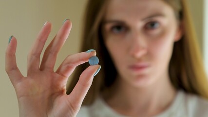 A little girl holds a blue round unpacked tablet at face level.