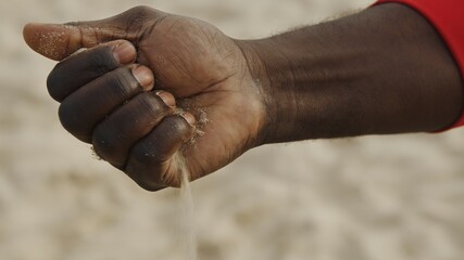 Sand in the hands of men. Close up view of sand running through a man's hands. Sand falling from hand. High quality photo