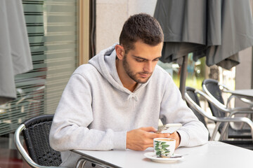 casual style young man with beard and mobile phone on cafe terrace