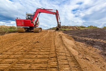 The modern excavator performs excavation work on the sand road .Road Construction and working of...