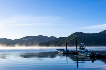 Fototapeta na wymiar 奥日光　湯気が立ち込める早朝の中禅寺湖、桟橋とボート