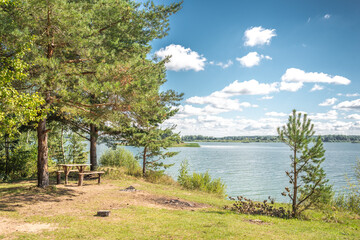 Landscape by the lake in the forest with a wooden table/Lake in the forest with a picnic table. On a sunny day.