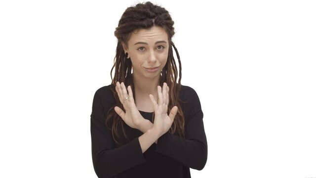 Pretty hipster girl with dreadlocks and ear tunnels, wearing black casual blouse, shaking hands to stop something, declining bad offer, saying no and rejecting proposal, white background