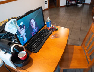 Fototapeta premium Coronavirus pandemic, social distancing means greetings and toasts are being made online. A woman is connected remotely and greets the man, they raise their wine glasses for a toast.