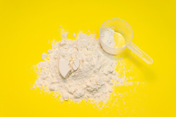 Measuring cup from a white powder whey protein on a yellow background