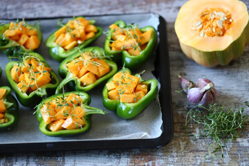 Selective focus. Green peppers stuffed with pumpkin pieces. Autumn dishes. Healthy food. Vegan lunch.