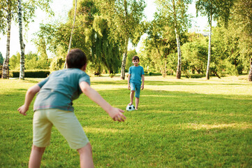 Two boys are playing in park with a soccer ball