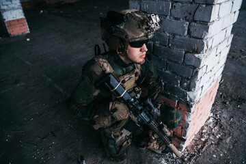Military soldier in the form holds in the hands an assault rifle, check possible enemies around the corner