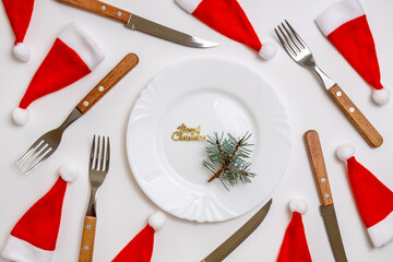 Traditional Christmas table place setting with empty white plate, linen napkin, cutlery with...