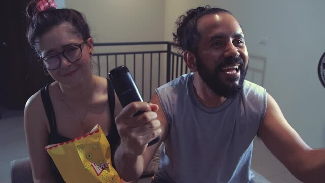 Pareja de novios casados comiendo palomitas viendo televisi&oacute;n pel&iacute;cula en casa terror miedo