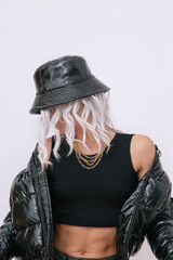  Sexy blonde model in fashion urban street outfit. Trendy black bucket hat and bomber. Daring Jewelry  Stylish Fall winter seasons. Rap hip hop vibes - obrazy, fototapety, plakaty
