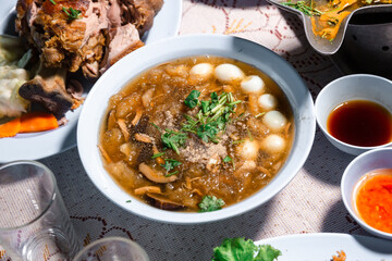 Chinese style soup; or braised fish maw in red gravy with eggs, mushroom, and bamboo shoot in white bowl. Braised Fish Maw in Red Gravy with crab in bowl.