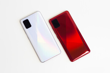 Two new modern smartphones, white and red on a white background, close up.