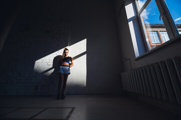 A young female athlete with a perfect body and abs is preparing for training in the early morning