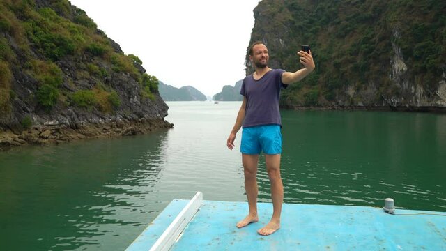 Young man taking selfie photo during cruise in Ha Long bay