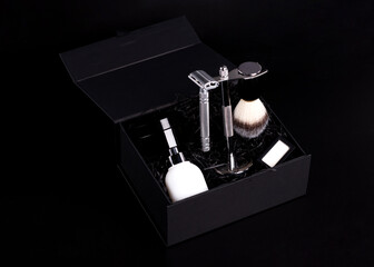 Razor and brush on stand,  perfume, balsam and blades in black box on a black background.