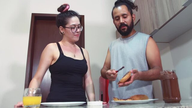 Joven pareja de mexicanos latino desayunando en casa comodos felices