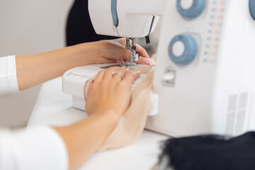 Caucasian young woman tailor works on sewing machine