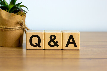 Concept word 'Q and A' on cubes on a beautiful wooden table, white background. House plant....