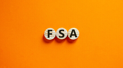 Concept words 'FSA, flexible spending account' on wooden circles on a beautiful orange background. Copy space, business concept.