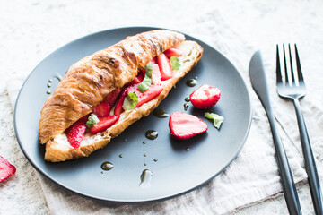Croissant with strawberries, soft cheese and honey