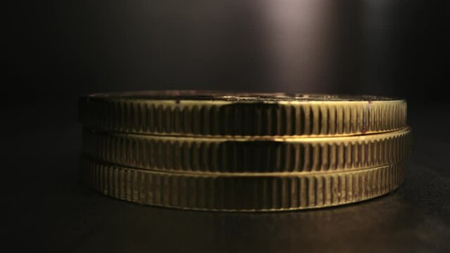 Extreme close up on the edge of Bitcoins as they fall, stacking on top and bouncing off of one another.
