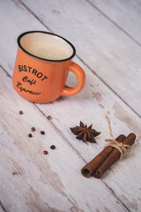 vintage orange coffee cup with cinnamon and star anise on a white wooden background. christmas spices. 