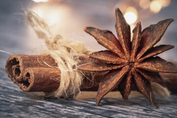Close-up of anise star and cinnamon stick around which a string is wrapped. autumnal tones and bokeh light in the background. holidays concept