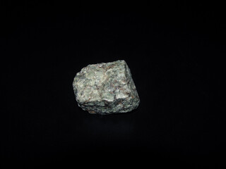 a sample of the urtite rock is gray-green on a black background