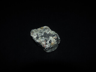 a sample of the urtite rock is gray-green on a black background