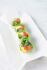 Food delivery, takeaway concept. Lunch box with bright spring roll in rice paper with salmon and herbs, vegetarian lunch. Japanese foo on light background. Japanese cuisine seafood