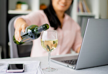 A Young Asian woman happily pouring white wine chatting on webcam with friends/ family social...