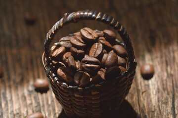 Coffee beans in a wicker basket on the background of a wooden table. Coffee composition.