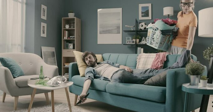 Lazy husband and disappointed wife tidying up